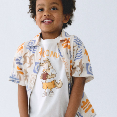 Criança de sorriso veste camisa estampada e t-shirt branca com estampa de crocodilo