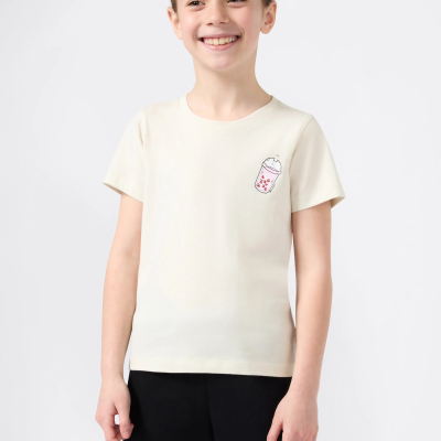Criança de camisa branca com impressão de copo de bebida e calças pretas com bolsos