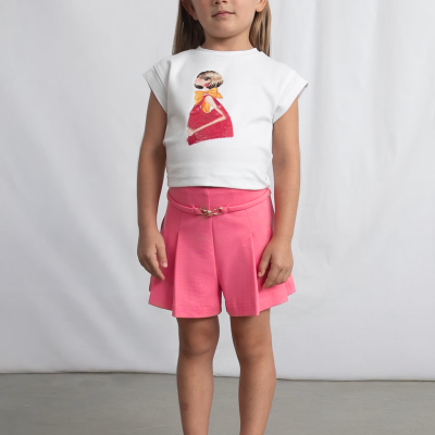 Criança com roupa branca e rosa numa sessão fotográfica de moda infantil.