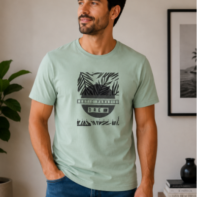 Homem com t-shirt verde claro estampada com folhas e texto preto, ao lado de planta e quadro na parede.