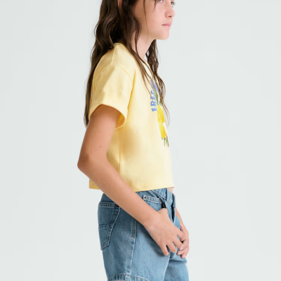 Rapaz de perfil com t-shirt amarelo claro e calções jeans azuis.