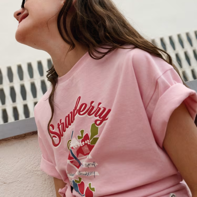 T-shirt rosa com estampa de morangos e calças cinzentas com padrão texturizado
