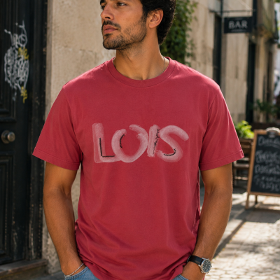 T-shirt vermelha com estampa LOIS usada por homem em rua urbana