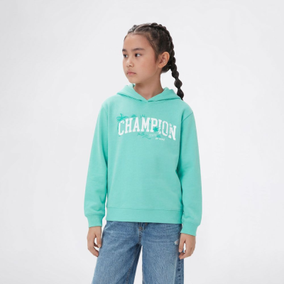 Camisola verde água com capuz e texto CHAMPION, calças de ganga azuis em fundo branco