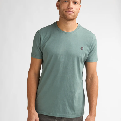 Homem a usar t-shirt verde e calças cinzentas sobre fundo branco