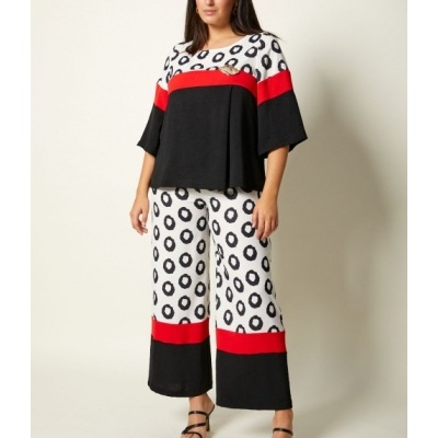 Conjunto feminino com blusa e calças largas com padrão de círculos pretos e detalhes em vermelho e preto