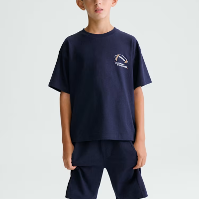 Menino com roupa desportiva azul escura com texto e desenho de bola