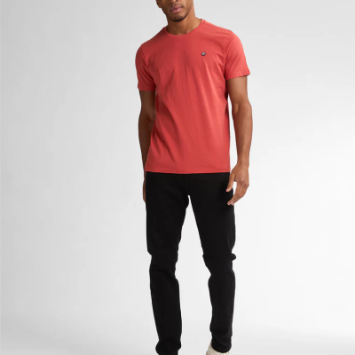 Homem com t-shirt coral, calças pretas e ténis brancos