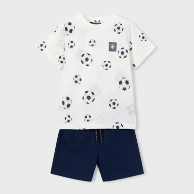 Conjunto infantil com t-shirt branca estampada de bolas de futebol e calções azuis escuros.