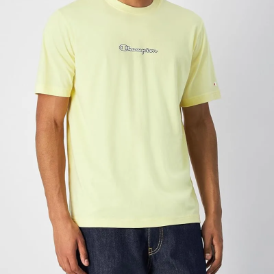 T-shirt amarela clara com logotipo Champion no peito e símbolo na manga, usada com calças jeans escuras.