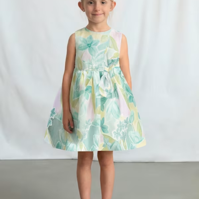 Vestido floral para menina com laço na cintura e sapatos brancos.