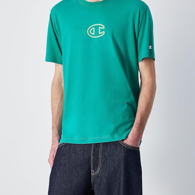Camiseta verde com logótipo e calças de ganga escuras, fundo branco