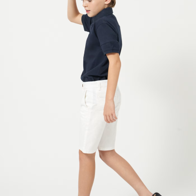 Menino com camisa polo azul, calções brancos, sapatos náuticos azuis e boné azul escuro.