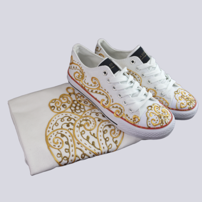 Ténis brancos com padrão dourado e saco branco com desenho dourado