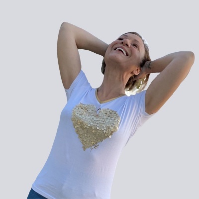 Mulher veste t-shirt branca com coração de lantejoulas douradas