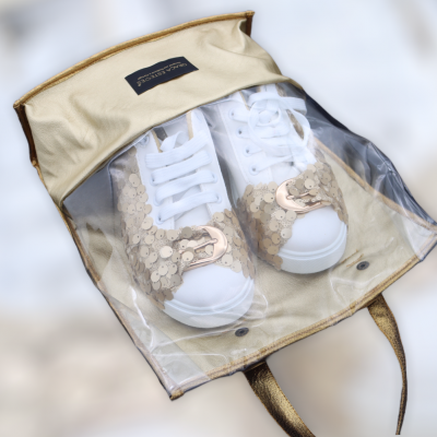 Sapatos brancos com lantejoulas douradas numa bolsa transparente