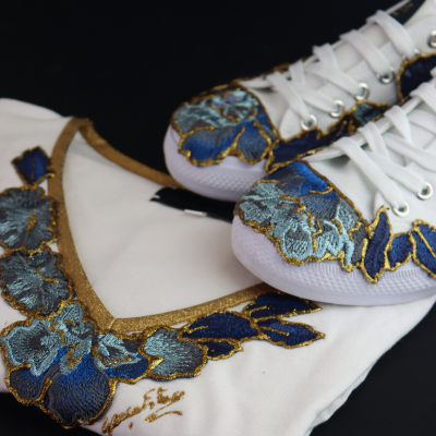 Camisola branca e sapatilhas com bordados florais em azul e dourado sobre fundo preto