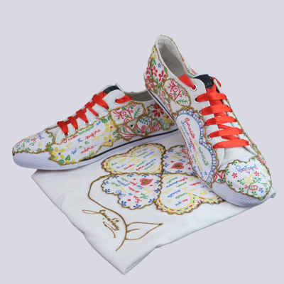 Tênis estampados florais coloridos com cadarços vermelhos sobre saco branco com padrão floral