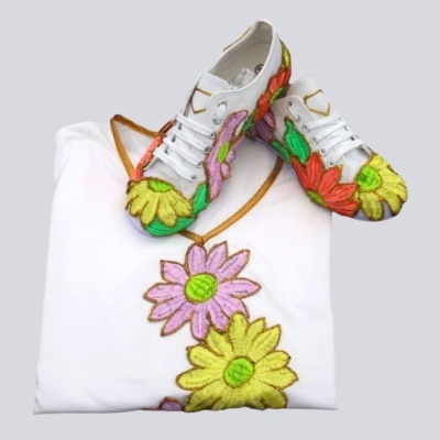 Sapatilhas e t-shirt brancas com bordados florais coloridos diferentes sobre fundo cinzento claro