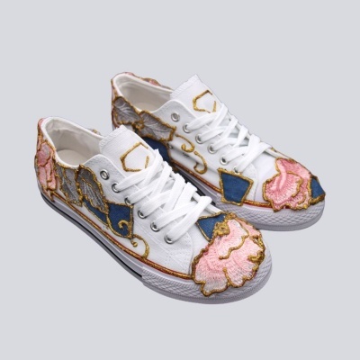 Ténis brancos com padrões bordados coloridos e sola branca