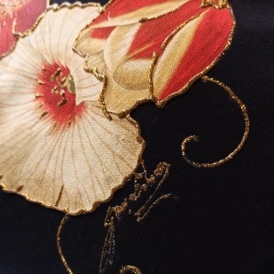 Tecido preto com padrão floral vermelho, creme e dourado com detalhes em fio dourado