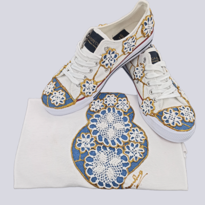 Sapatilhas brancas com aplicação de padrão floral em crochet azul, branco e amarelo, com peça de tecido branca com o mesmo padrão
