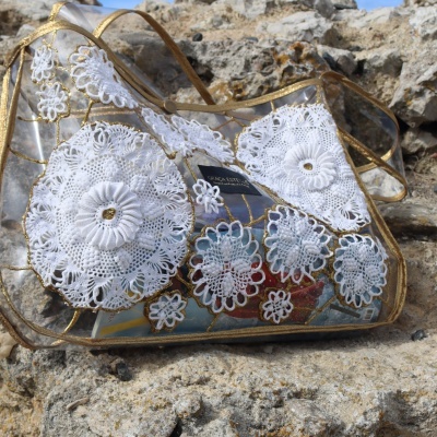 Bolsa transparente com bordados brancos em croché sobre rochas