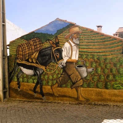 Mural exterior de homem e burro em cenário rural com vinhas