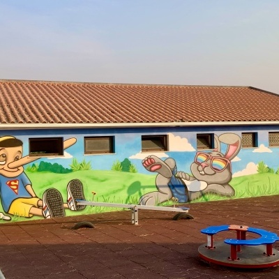 Mural colorido de Pinóquio e coelho numa parede de parque infantil.