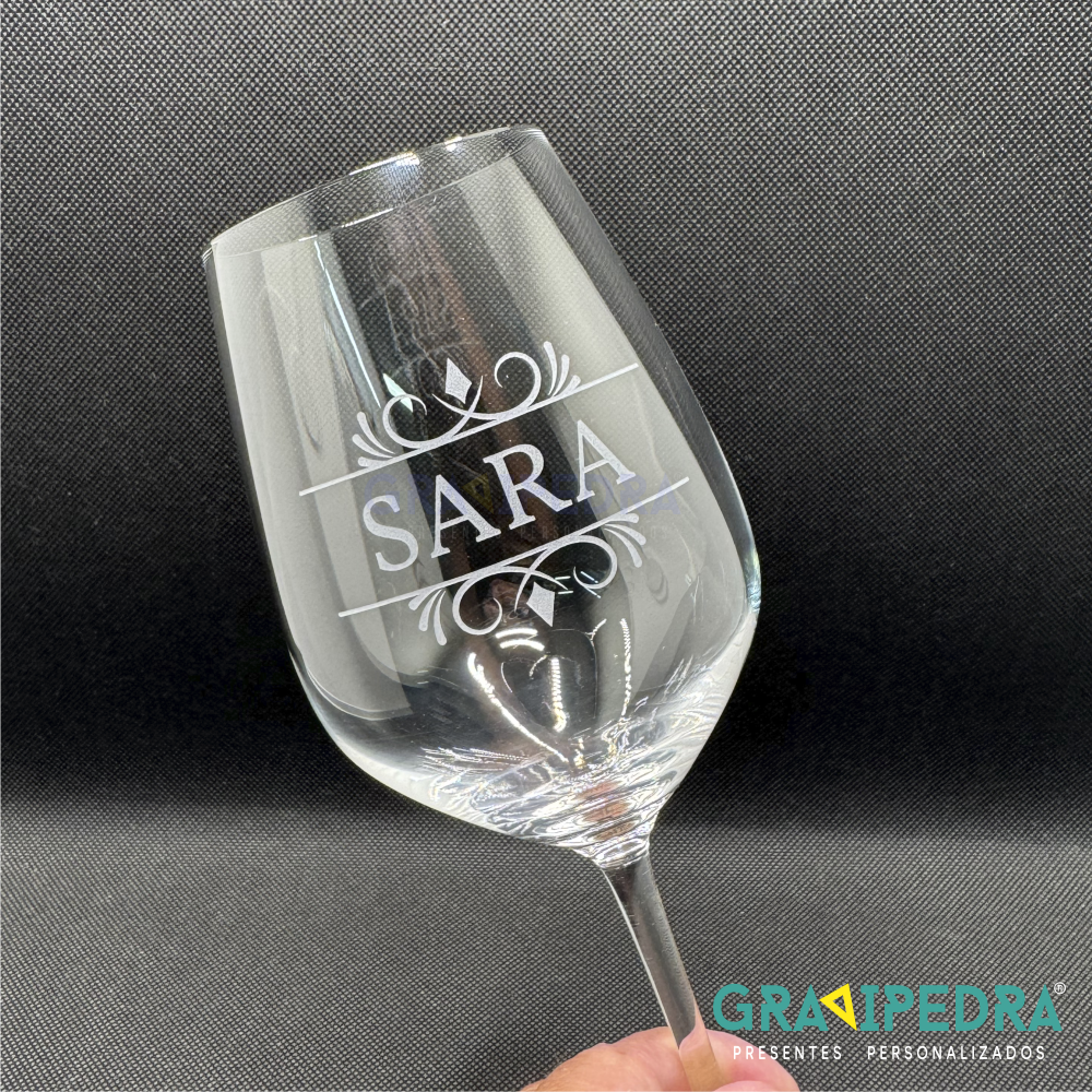 Copo em vidro personalizado - Personaliza com o teu Nome - CVFG19 Copo de vinho gravado com 'SARA' e decoração floral, fundo preto.
