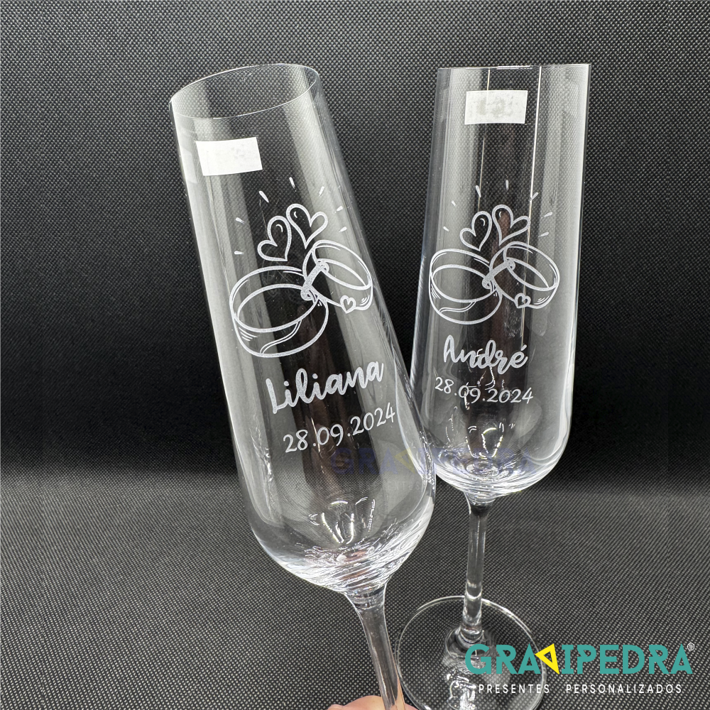 Pack 2 Copos em vidro personalizados - Noivos - CVCND07A Duas taças de champanhe gravadas com nomes, data e desenhos de alianças sobre fundo preto