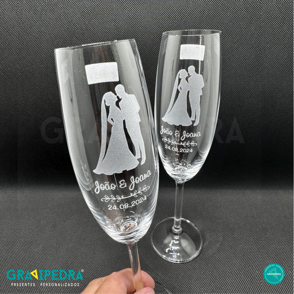 Pack 2 Copos em vidro personalizados - Noivos - CVCND19A Dois copos de vidro com gravação de casal de noivos, nomes João & Joana e data 24.08.2024 sobre fundo preto.