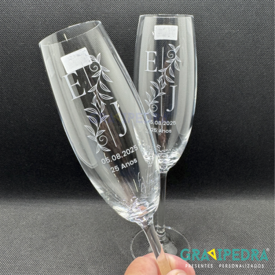 Duas taças de champanhe gravadas com letras, data e padrão floral em fundo preto