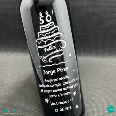 Garrafa preta com mensagem personalizada de aniversário e bolo com velas 50