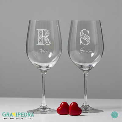 Dois copos de vinho personalizados com nomes e iniciais, junto a corações vermelhos