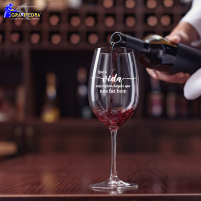 Copo de vinho com texto em português a ser preenchido com vinho tinto em bar