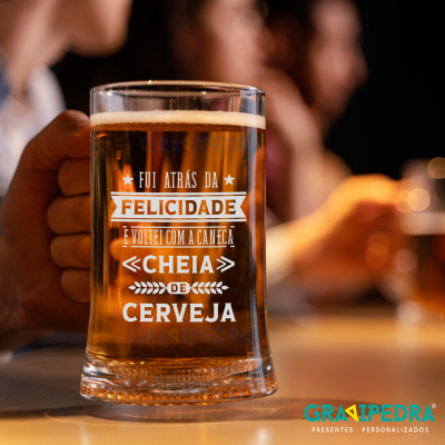Copo de cerveja com texto impresso em português em ambiente com pessoas ao fundo