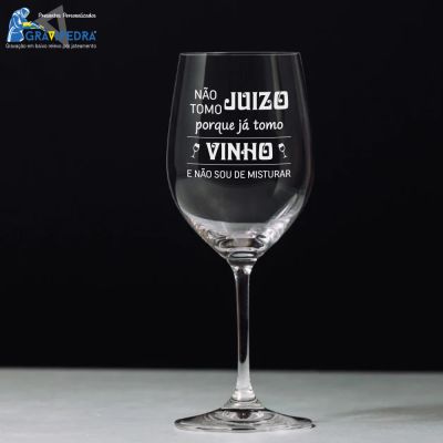 Copo de vinho transparente com texto motivacional em branco.