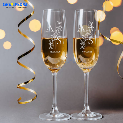 Duas taças de champanhe gravadas com letras A e S e data 15.01.2025, com fitas douradas ao redor.