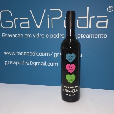 Garrafa preta decorada com etiquetas de coração e texto de feliz São Valentim com fundo azul e texto branco GraViPedra