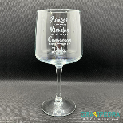 Copo de vidro com pé alto e mensagem gravada em branco sobre fundo preto