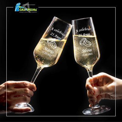 Duas taças de champanhe personalizadas a brindar num fundo preto