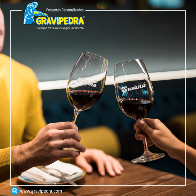 Duas taças de vinho tinto com nomes gravados em branco sendo erguidas para brinde.
