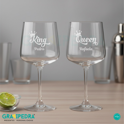 Duas taças de vinho personalizadas com textos 'King Pedro' e 'Queen Rafaela' em ambiente interno.