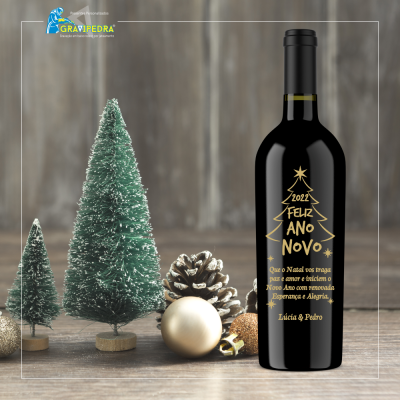 Garrafa de vinho preta com rótulo dourado na mesa perto de decoração de Natal