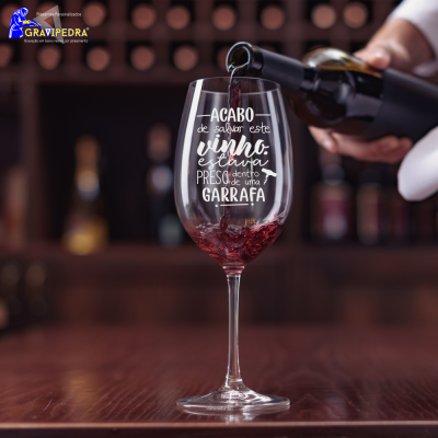 Copo de vinho com texto impresso e vinho sendo servido em ambiente de bar