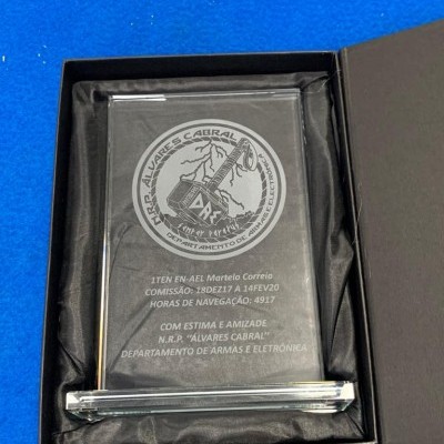 Placa de vidro gravada em caixa preta sobre superfície azul