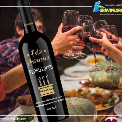 Garrafa de vinho preta com etiqueta personalizada de aniversário e pessoas a brindar ao fundo