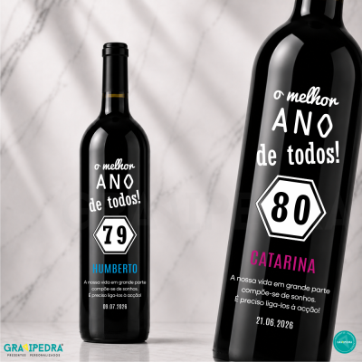 Garrafas de vinho tinto com rótulos personalizados e texto em branco, azul e rosa sobre fundo marmoreado.