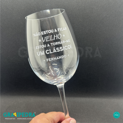 Copo de vinho transparente com mensagem personalizada em português.